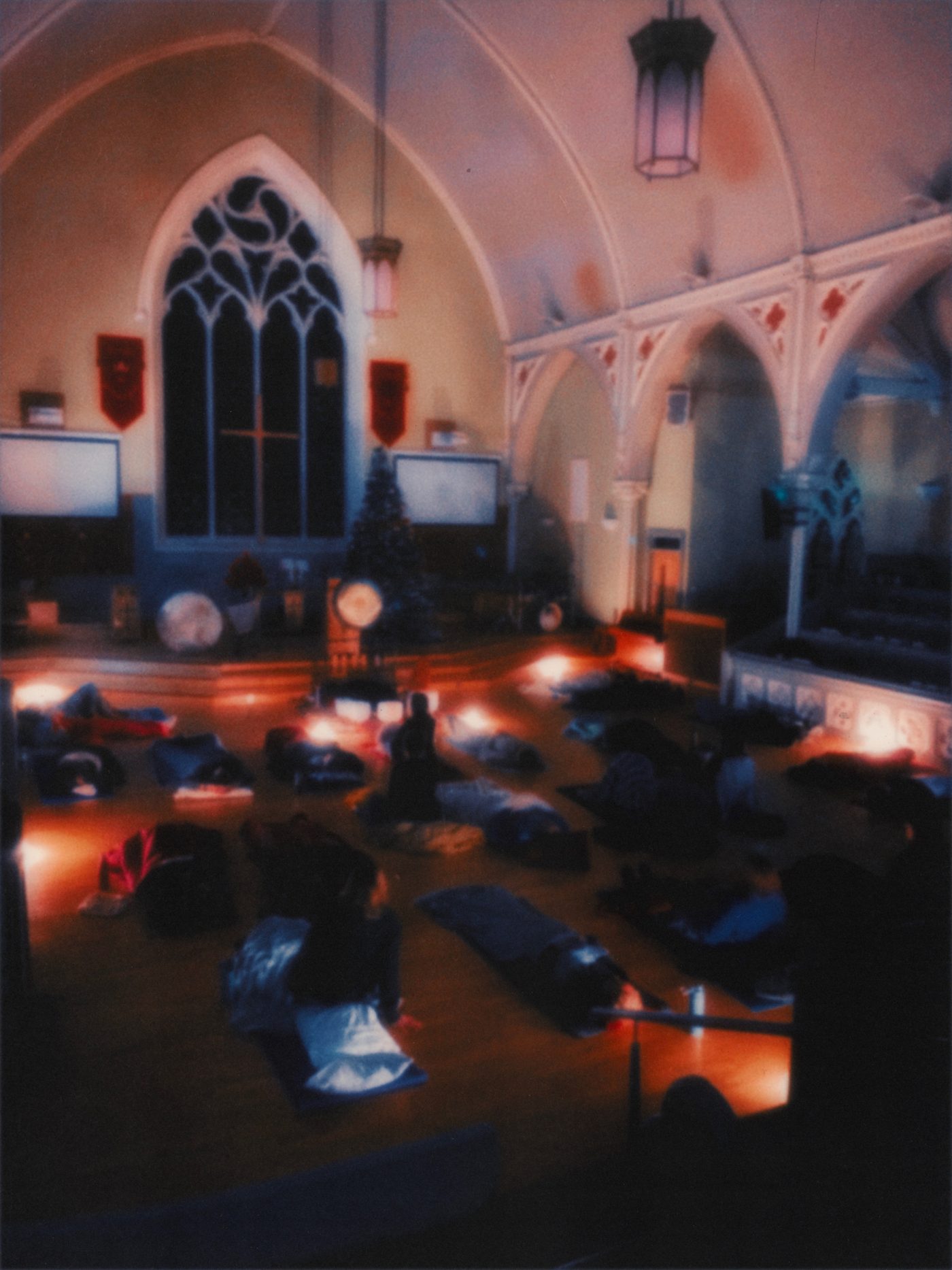 A Glasgow Soundbath session in a candlelit church hall, people lying on the floor under blankets